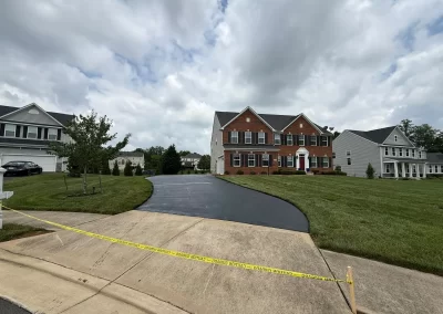 A red brick suburban house with a newly paved driveway blocked by caution tape.