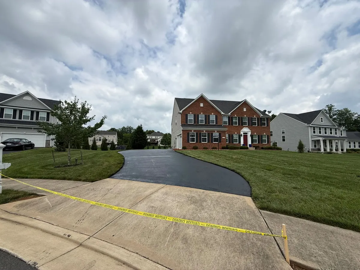 A red brick suburban house with a newly paved driveway blocked by caution tape.