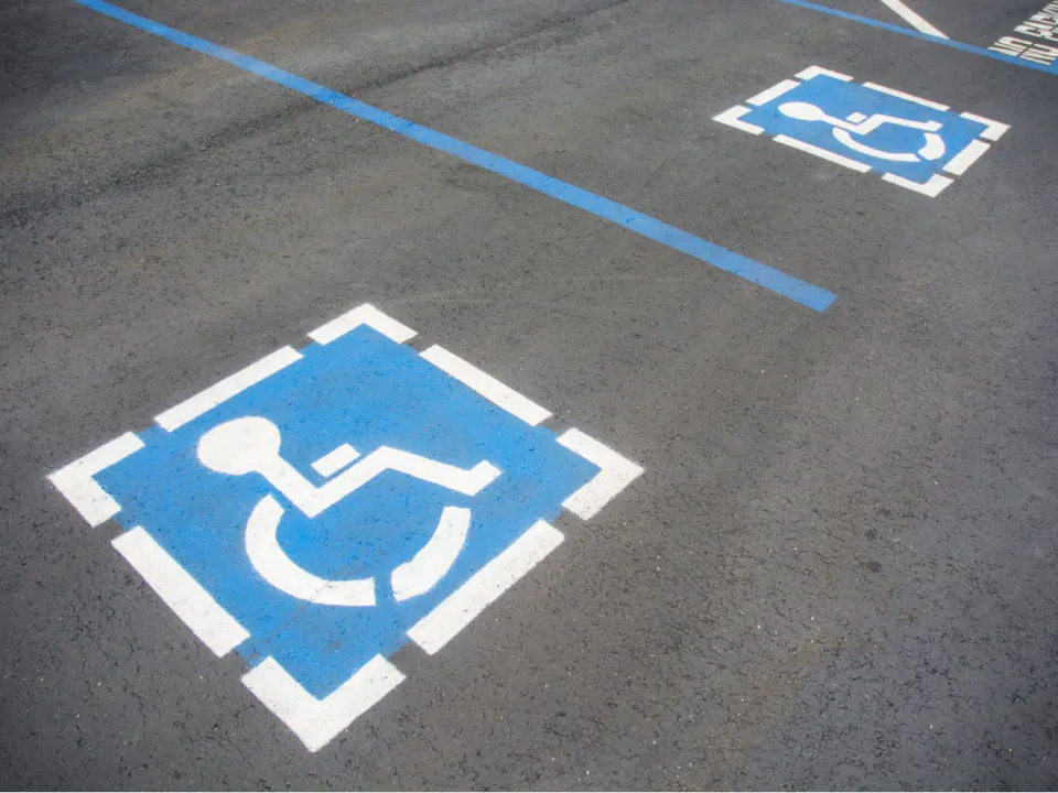 Two handicap parking space symbols painted on asphalt.