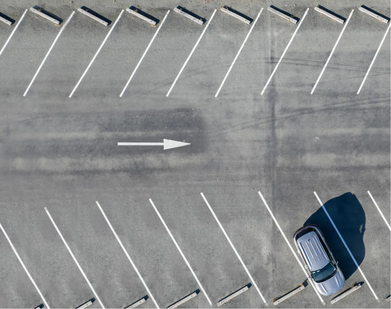 Aerial view of a parking lot with one silver car parked in a space.