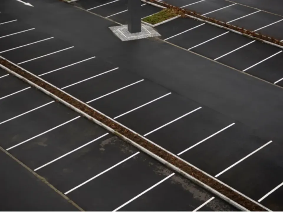 High-angle view of an empty asphalt parking lot with white marked spaces.