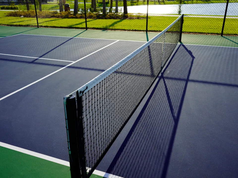 An empty pickleball court with a center net, viewed from the side.