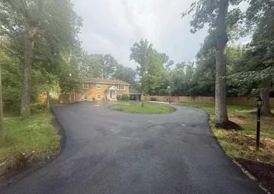 A brick house at the end of a circular asphalt driveway.