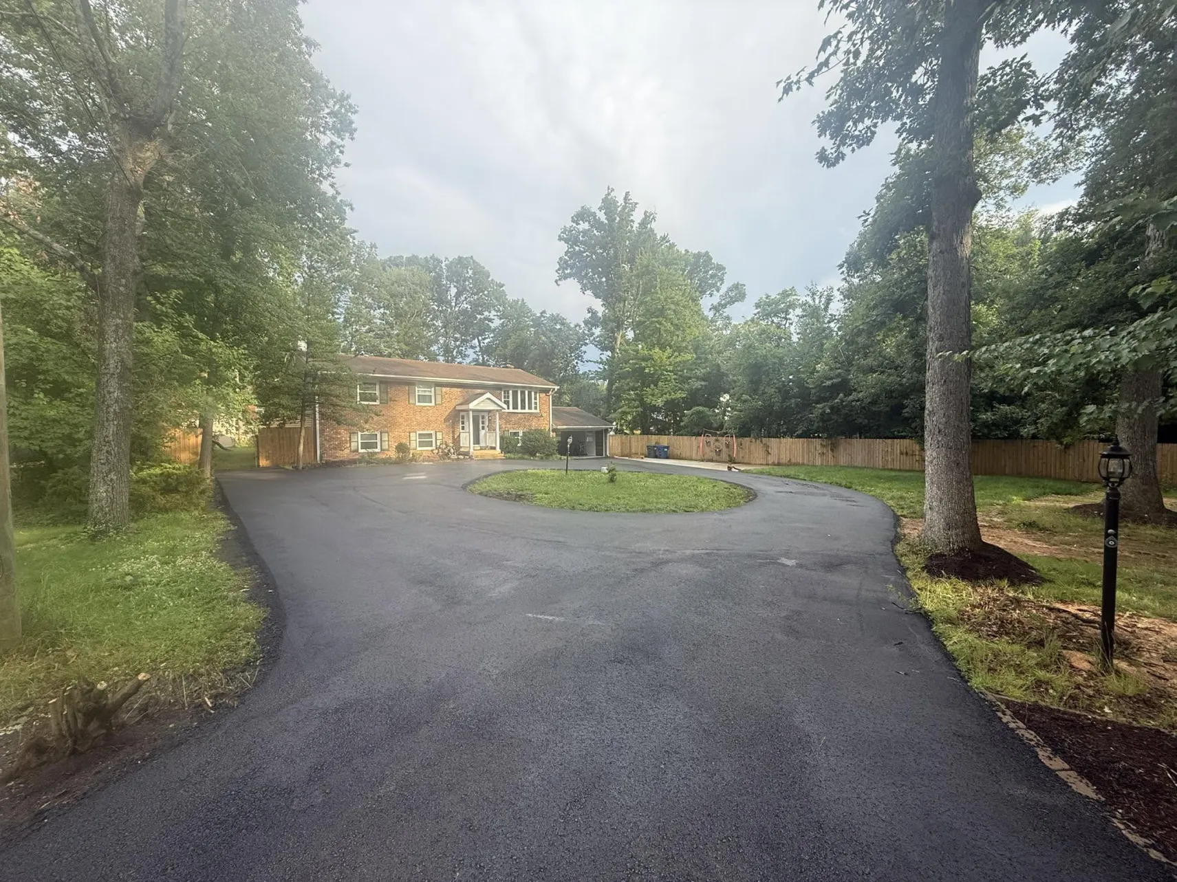 A brick house at the end of a circular asphalt driveway.
