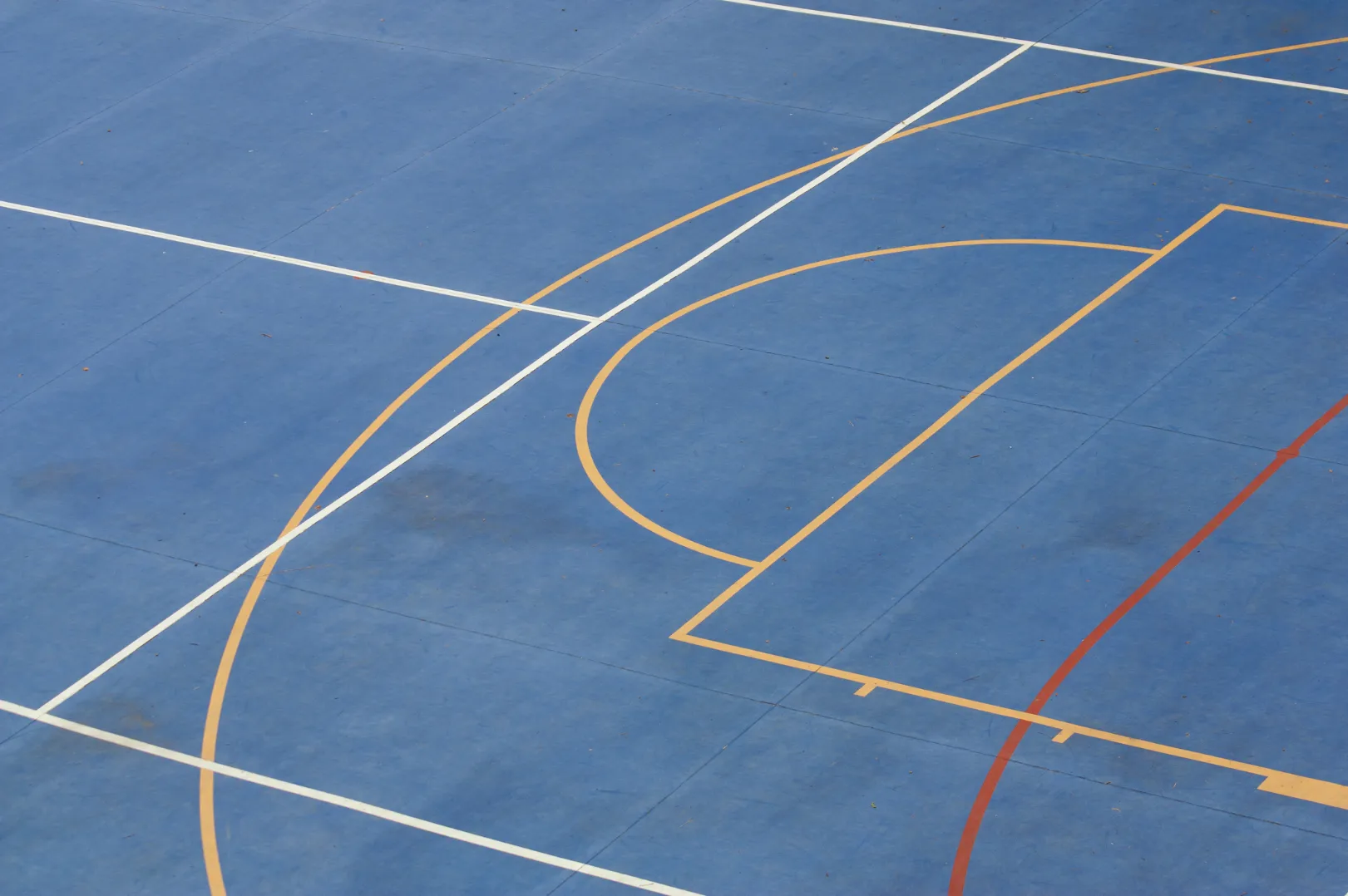 sports-h Blue sports court surface with white, yellow, and red painted lines.